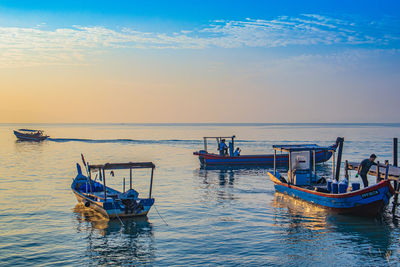 Boat moored in sea against sky during sunset