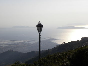 Street light by sea against sky