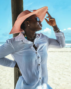 African woman standing in the shade with hat and sunglasses on the beach. bojo beach accra ghana 
