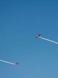 Low angle view of airplane flying against clear blue sky