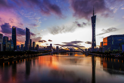 Bridge over river by buildings against sky in city