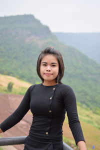 Portrait of smiling young woman standing by railing on observation point