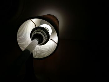 Low angle view of illuminated electric lamp against black background