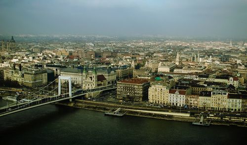 High angle view of bridge over river amidst buildings in city against sky