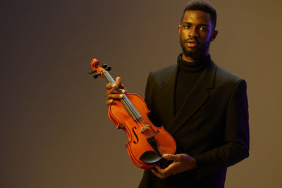 Young man playing violin against wall