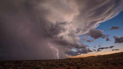 Panoramic view of lightning over landscape against storm clouds