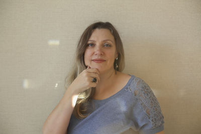 Portrait of young woman standing against wall