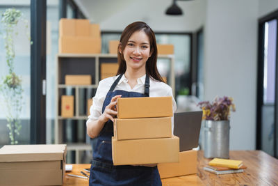 Portrait of smiling young woman holding box