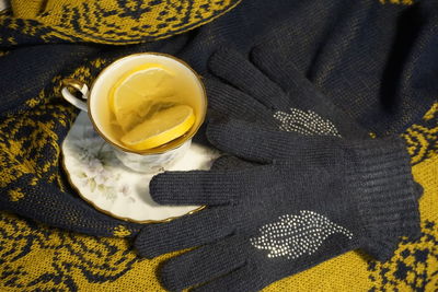 High angle view of a cup of tea with lemon and winter gloves on the table