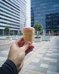 Close-up of woman holding ice cream cone on street in city