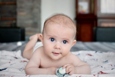 Portrait of cute baby lying on bed at home