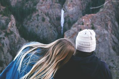 Rear view of couple sitting at rock formation