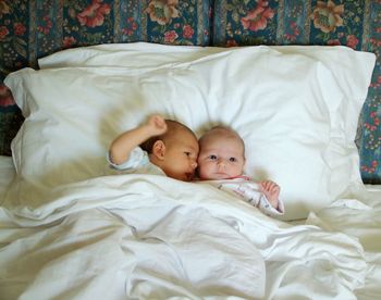 Cute siblings lying on bed at home