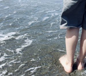 A young boys feet being hit by the pacific ocean for the first time