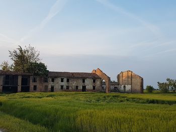 Abandoned house on field against sky