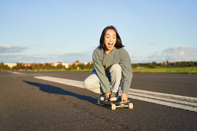 Portrait of young woman standing on road against sky