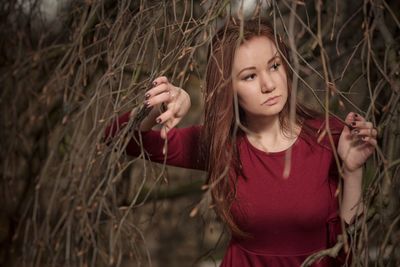 Portrait of young woman standing by plants