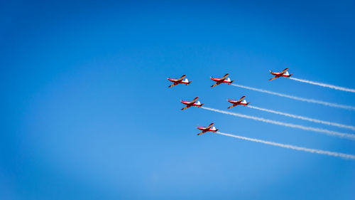 Low angle view of airshow against blue sky