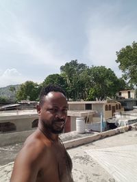 Portrait of shirtless man in swimming pool against trees