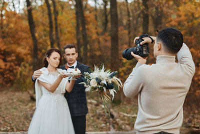 Rear view of woman photographing with bouquet