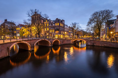 Bridge over river in city against sky