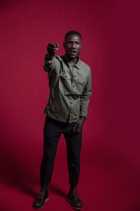 Portrait of young man standing against red background