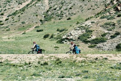 Side view of friends riding bicycle against mountain