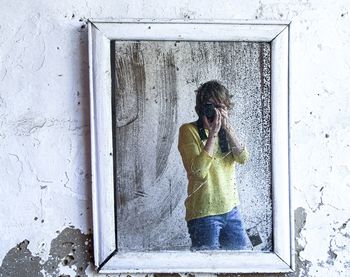 Woman looking at camera while standing against window