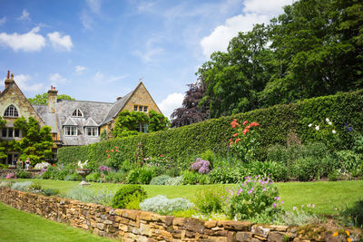 Scenic view of house amidst trees and plants against sky