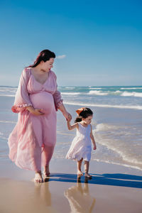 Pregnant woman walking with daughter at beach