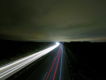 Light trails on road against sky at night