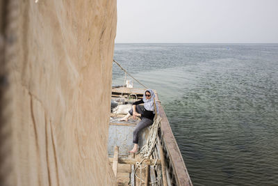 Man fishing in sea against clear sky