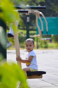 Portrait of cute girl sitting on outdoor play equipment