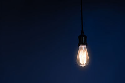 Low angle view of illuminated light bulb against clear sky