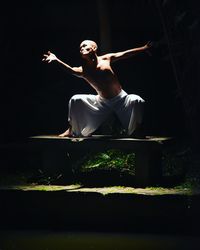 Young man with arms outstretched against black background