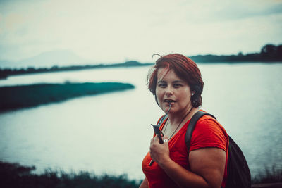 Portrait of woman standing against lake