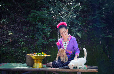 Woman with cats sitting on table against trees