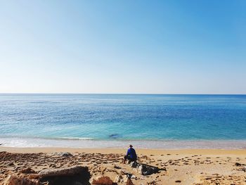 Rear view of man on beach against clear sky