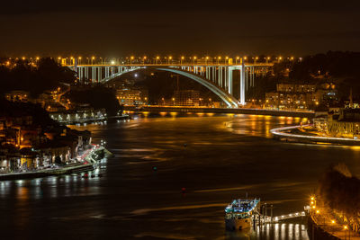 Illuminated bridge over river in city against sky at night