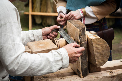 Midsection of man shaving wood with woman at workshop