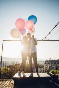 Low angle view of woman with balloons against clear sky