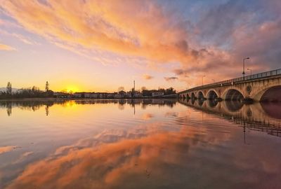 Bridge over river against sky during sunset