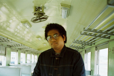 Portrait of young man standing against ceiling