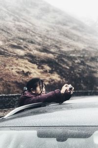 Portrait of young woman relaxing on car