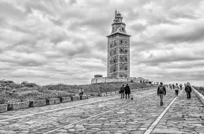 Group of people walking on lighthouse against sky