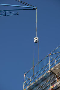 Low angle view of crane against clear blue sky