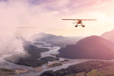 Airplane flying over mountains against sky