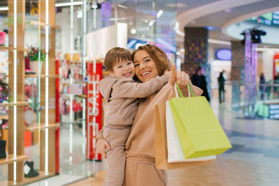 Happy and satisfied mother and little boy child with shopping bags in the store. go shopping