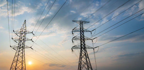 Low angle view of silhouette electricity pylon against sky during sunset