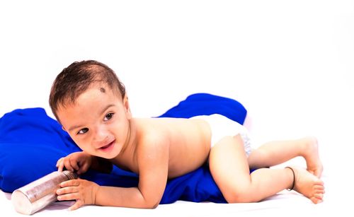 Portrait of boy lying on bed against white background